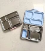 Two Kaally Bento 4+ lunchboxes open side by side on a marble bench with pink and blue lids