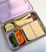 Lilac-lid Bento 4+ packed with a sandwich, carrot sticks, cucumber and greens