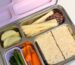 Kaally stainless steel bento lunch box with lilac lid packed with sandwiches, apple, carrots and snacks