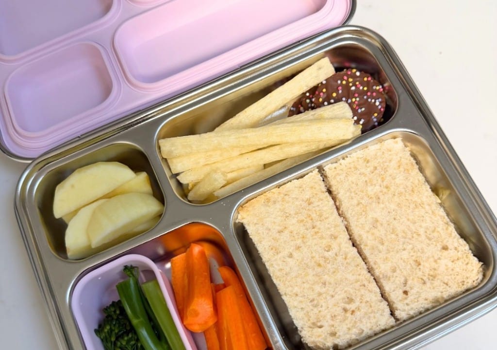 Kaally stainless steel bento lunch box with lilac lid packed with sandwiches, apple, carrots and snacks