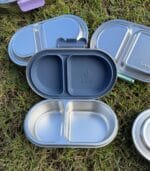Kaally Snack Box New 2026 Edition open in Denim on grass, showing the deeper lid and sealed compartments